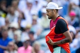 Australia's Nick Kyrgios looks down on court as he holds his tennis singlet during a match.