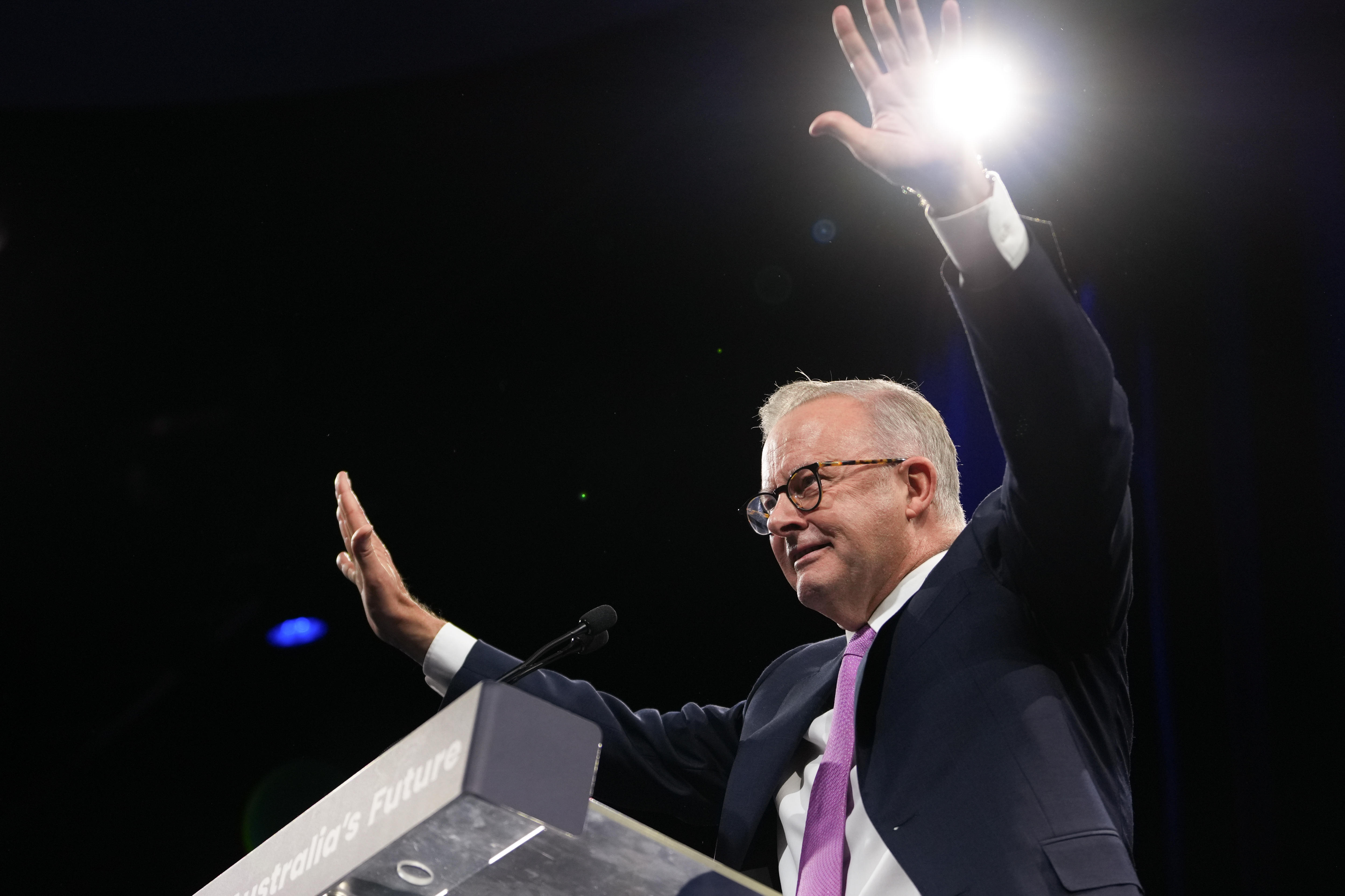Albanese on stage smiling with hands in the air