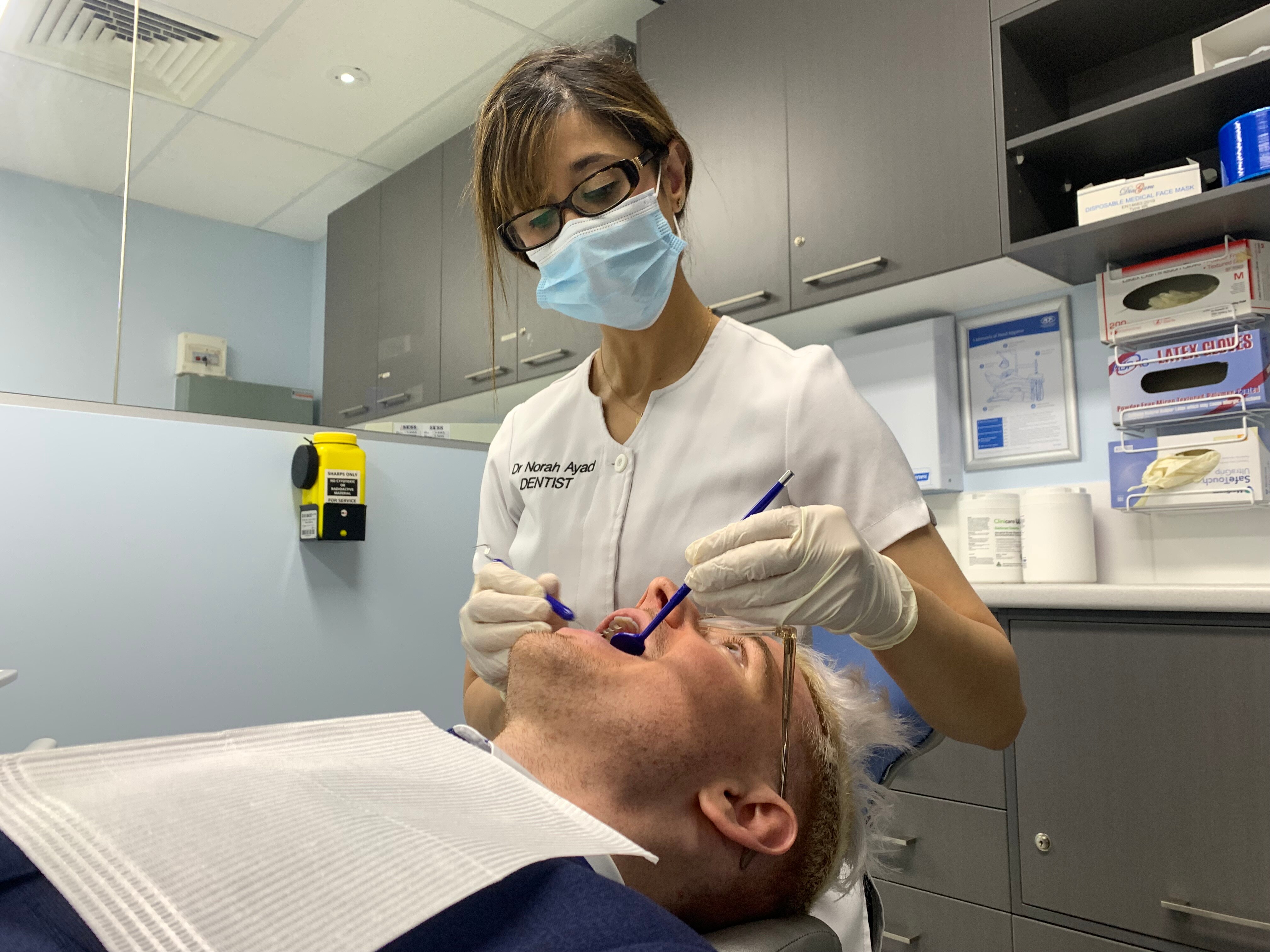 Dr Norah Ayad working on a patient's open mouth in her dentistry clinic
