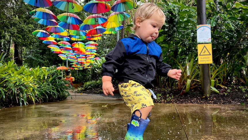 A one-year-old boy playing in the rain puddles.