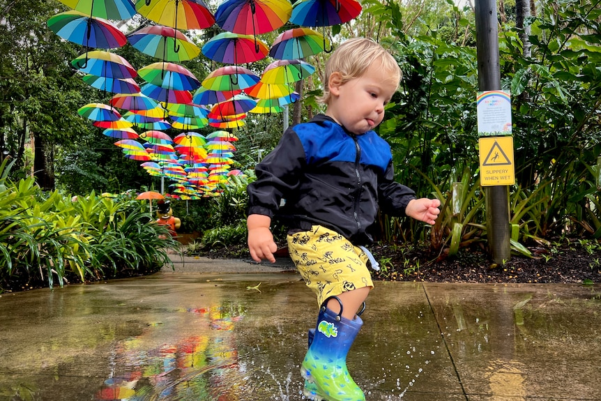 A one-year-old boy playing in the rain puddles.