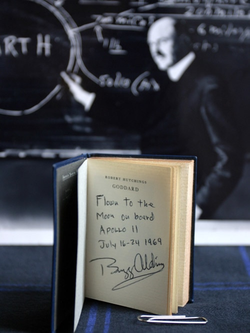 An open book with hand written note, "Flown to the Moon on board Apollo 11, July 16-24 1969, Buzz Aldrin".