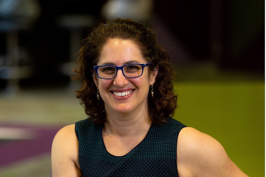 Close up of a smiling woman wearing glasses and a black top.