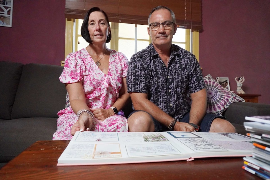 A man and a woman sit in front of a book.