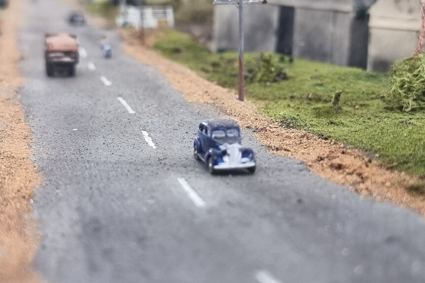 A miniature blue care on a road.
