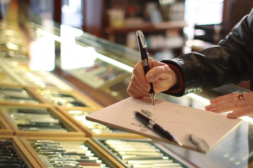 A customer makes some scribbles on a note pad in a shop.