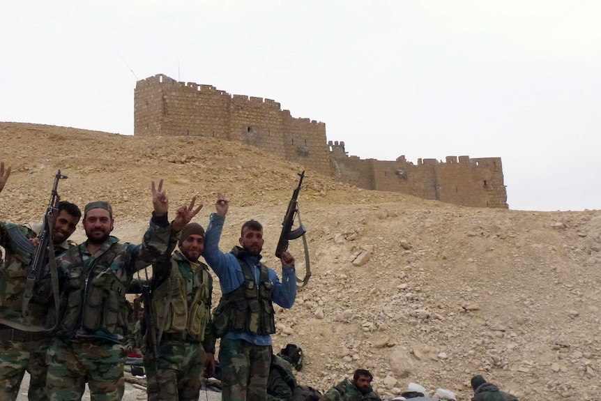 Syrian pro-government forces gesture next to the Palmyra citadel