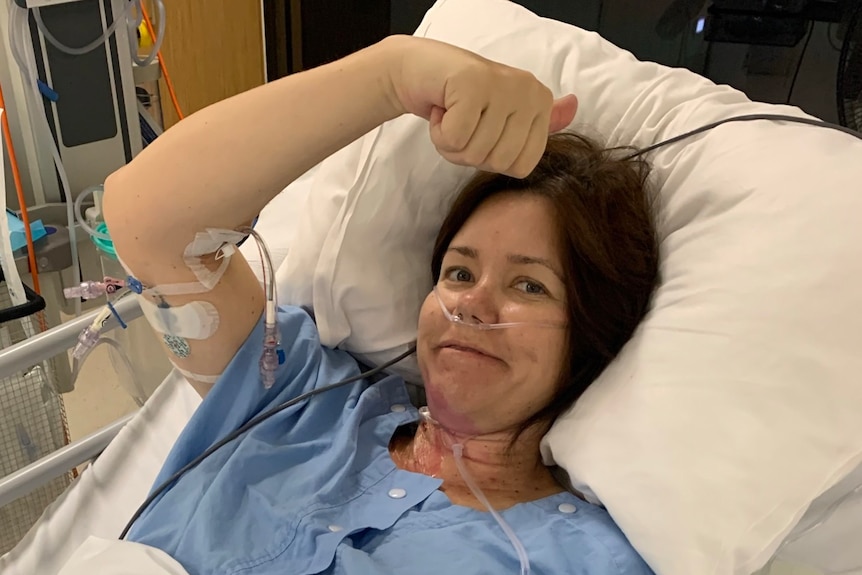 A woman in blue scrubs in a hospital bed