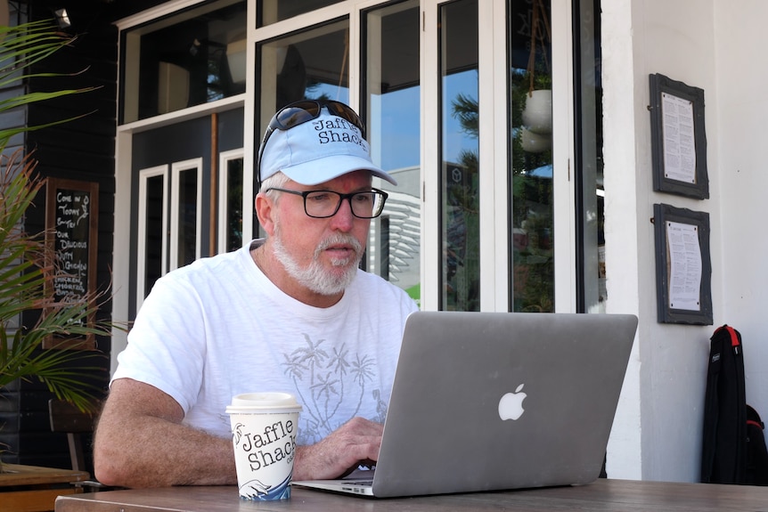 Christian Watters sits at a table looking at a laptop.