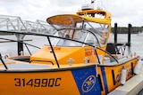 A yellow marine rescue boat tied to a dock