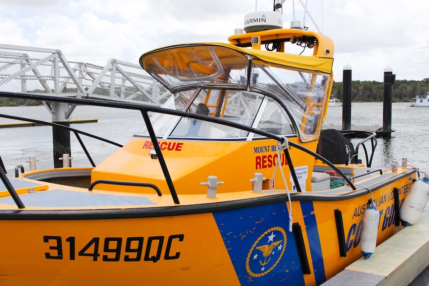 A yellow marine rescue boat tied to a dock