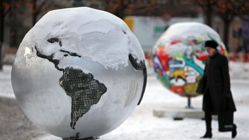 A woman walks by globe sculptures in Copenhagen