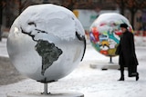 A woman walks by globe sculptures in Copenhagen