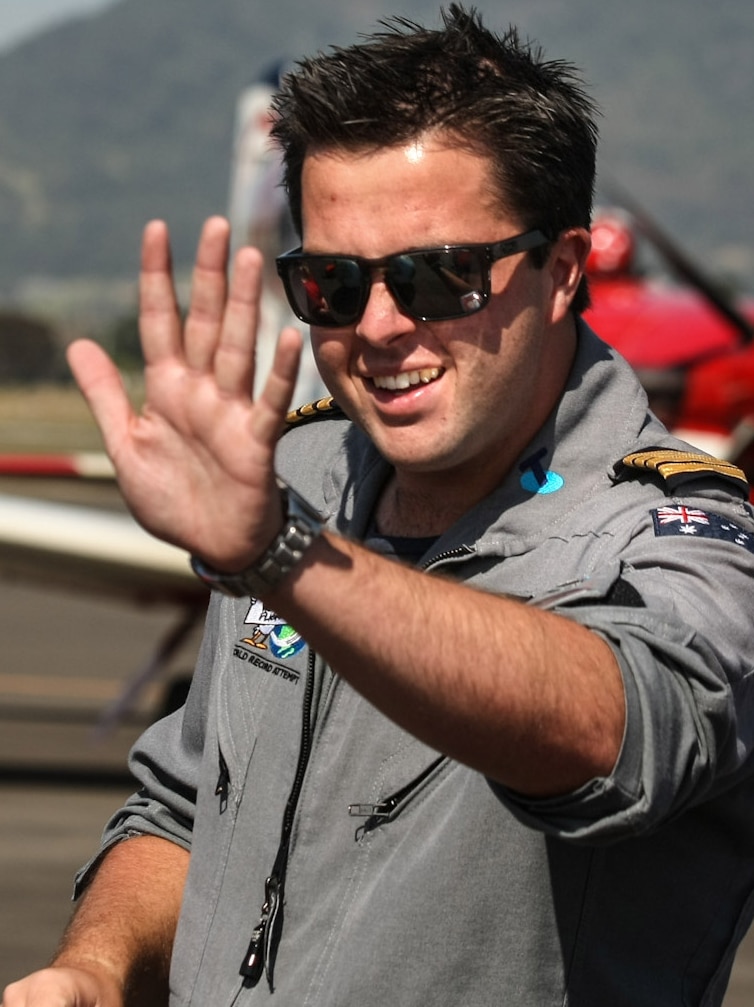 Ryan Campbell, wearing sunglasses, waves as he stands next to a plane.