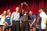 Prime Minister Malcolm Turnbull posing for a selfie with a group of students with a red velvet curtain the background.