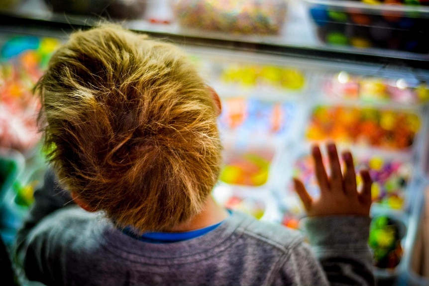 Blonde hair boy looks at lolly counter