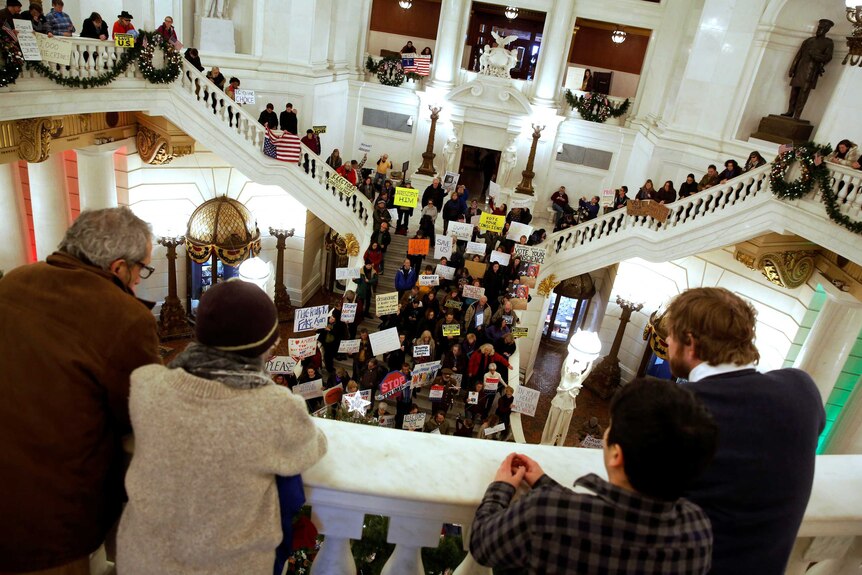 Protesters stand at a balcony and on the staircase protesting with signs