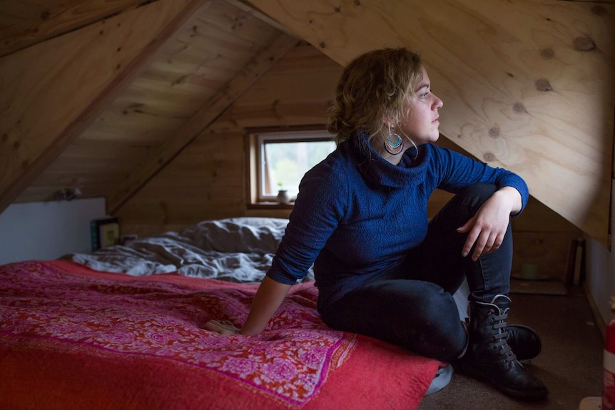 Sarah Smethurst sits on her bed in the loft of her home.