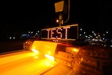 An LED sign that says 'test' sits on top of a police car in front of a red light camera