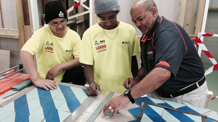Participants in a NSW TAFE trade readiness program learning wall and floor tiling.