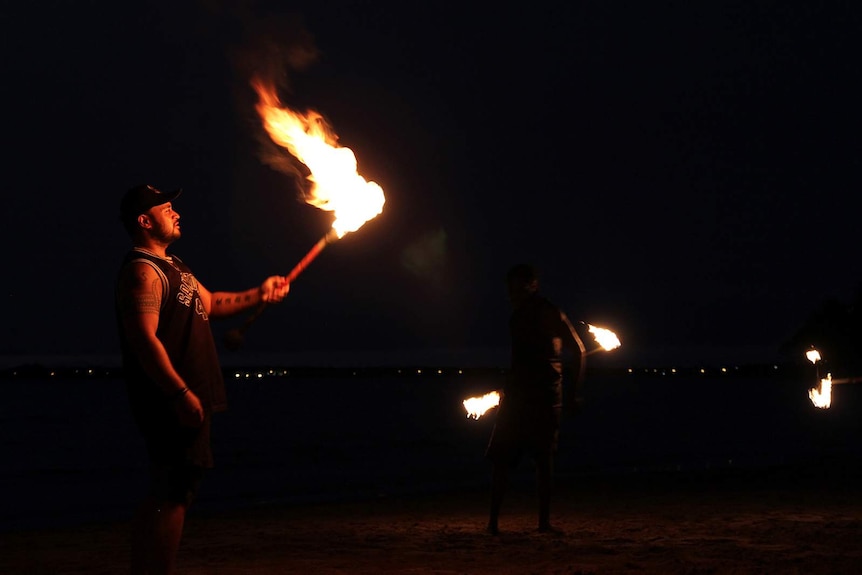 Hale Wilson lights his Samoan fire knife on the foreshore of Mindil Beach.