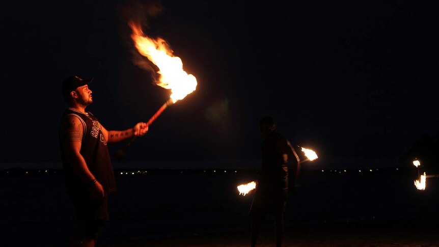 Hale Wilson lights his Samoan fire knife on the foreshore of Mindil Beach.