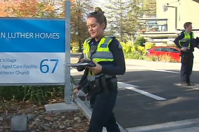 A female police officer walks in front of the entrance to Martin Luther Homes.