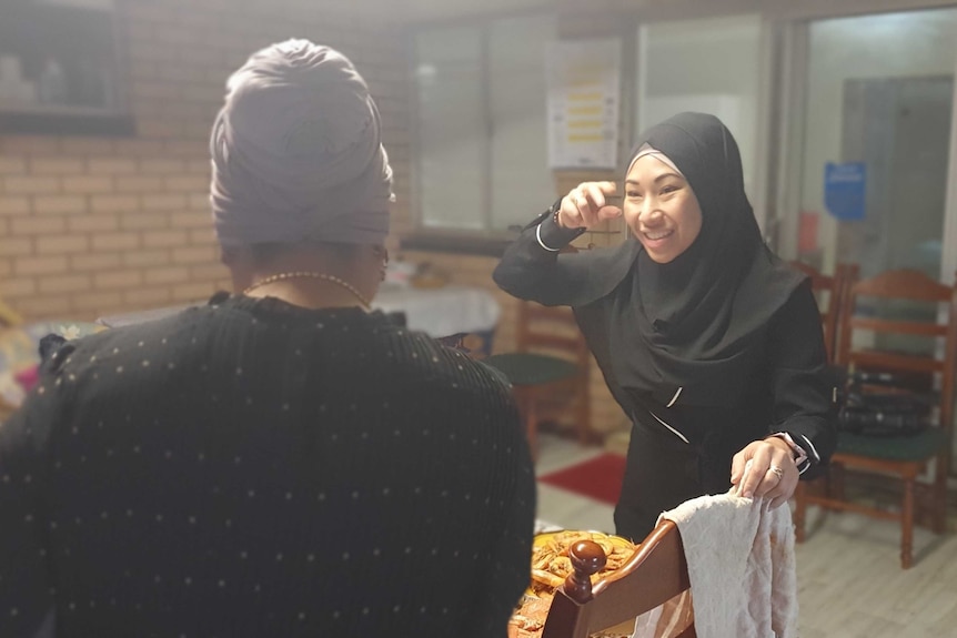 Two Muslim women talk at dining table