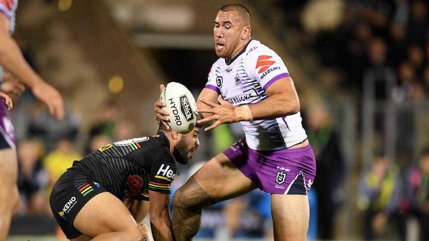 NRL player runs with the ball as his opponent braces to tackle him.