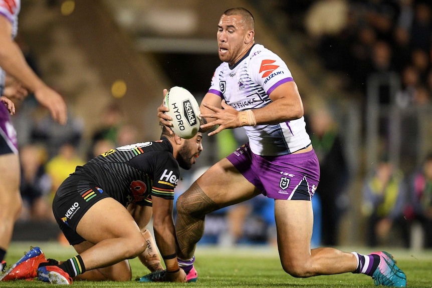 NRL player runs with the ball as his opponent braces to tackle him.