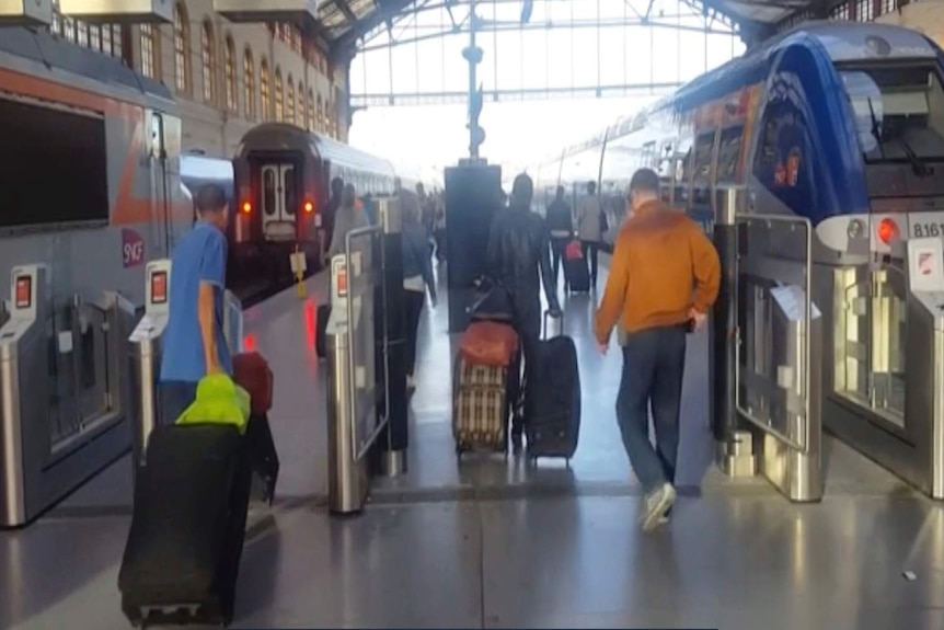 Passengers walk through gates on platform at Marseille train station.