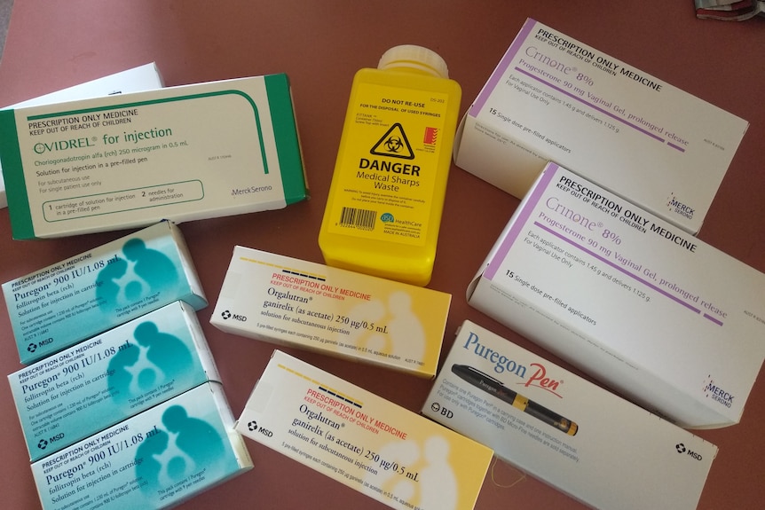 various boxes of medicine typically used during IVF treatment sitting on a brown tabletop.