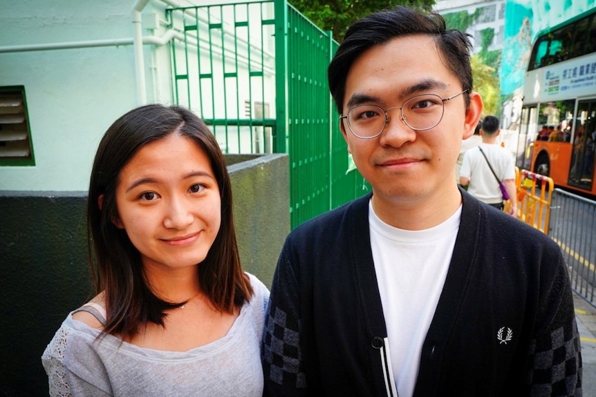 A sister and brother stand in the street in Hong Kong.