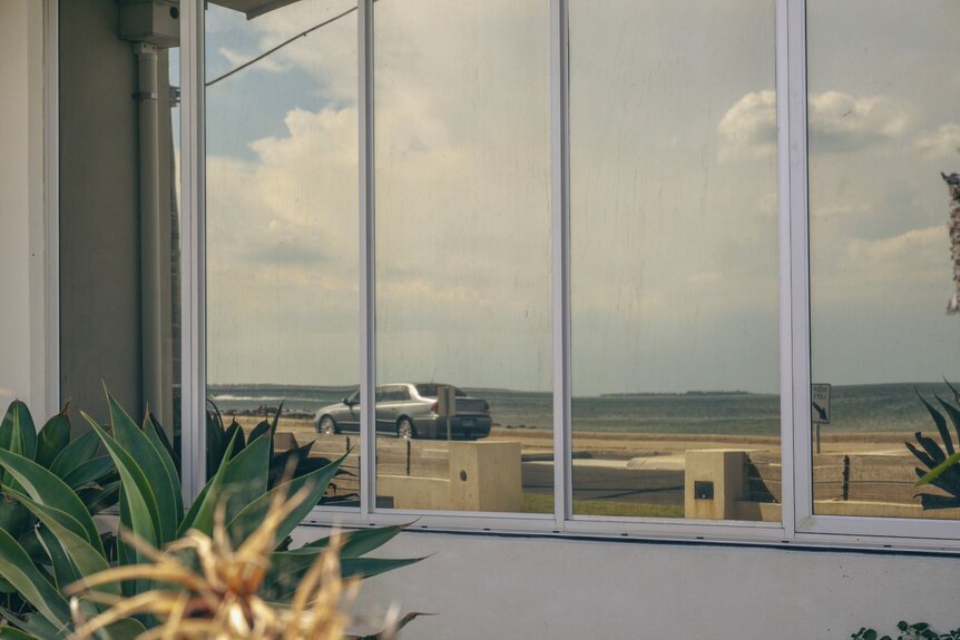 A view of the Esplanade at Altona, seen through a reflection on a house window