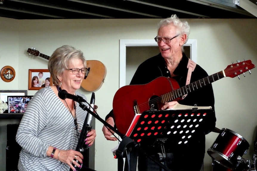 A man playing the guitar and a woman playing the clarinet together