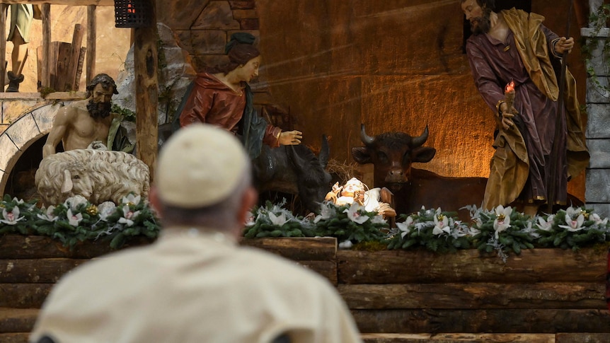 Pope Francis looks at a statue of baby Jesus in St Peter's Basilica at the Vatican