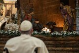 Pope Francis looks at a statue of baby Jesus in St Peter's Basilica at the Vatican