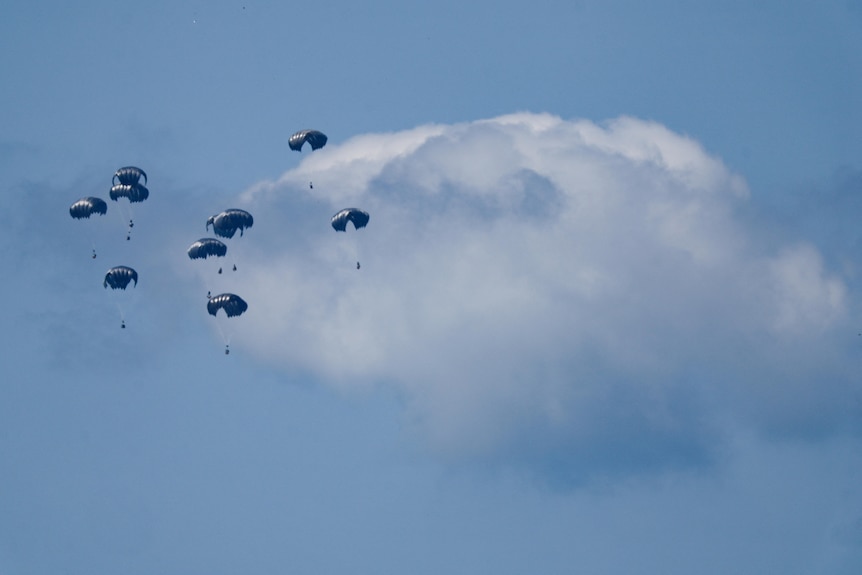 Parachutes falling through a blue sky 