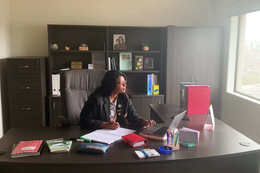 Avia Sanders studying at a big brown desk at her home.