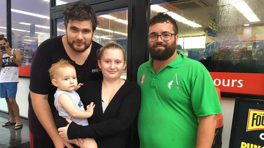 Keith Abrahams (far right in green shirt), another man, a woman and baby stand together.