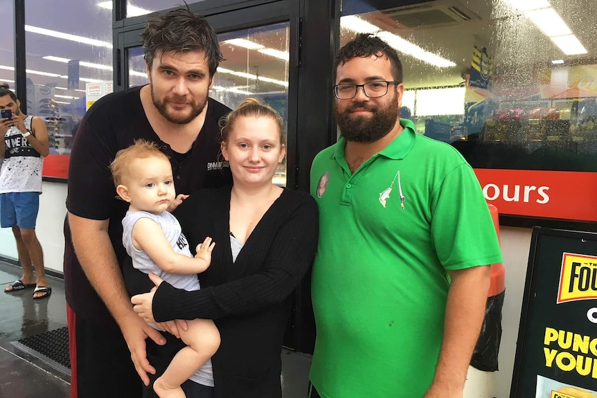 Keith Abrahams (far right in green shirt), another man, a woman and baby stand together.