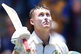 Australia batsman Marnus Labuschagne looks up into the sun and raises his bat during a Test.