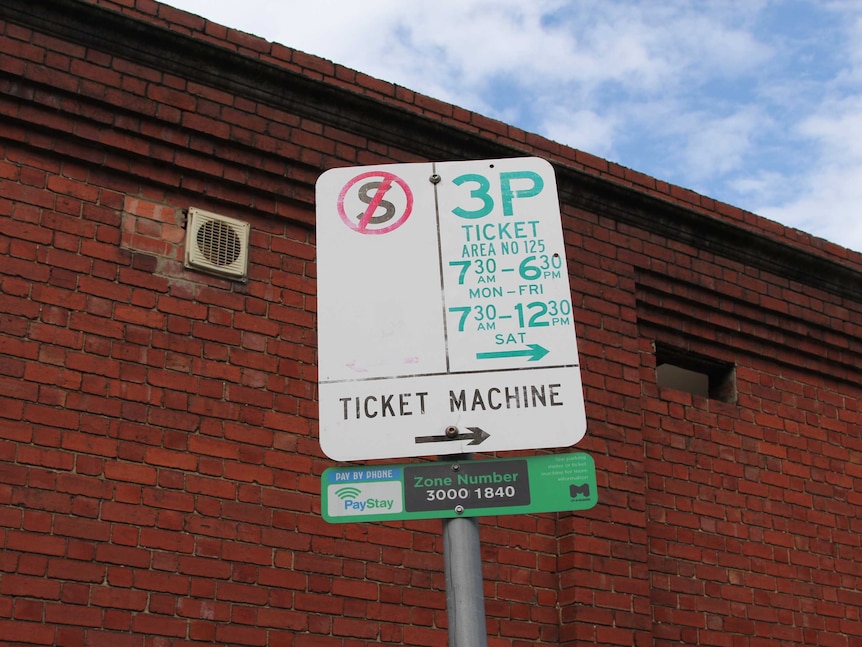 A parking sign displays times, symbols and arrows.