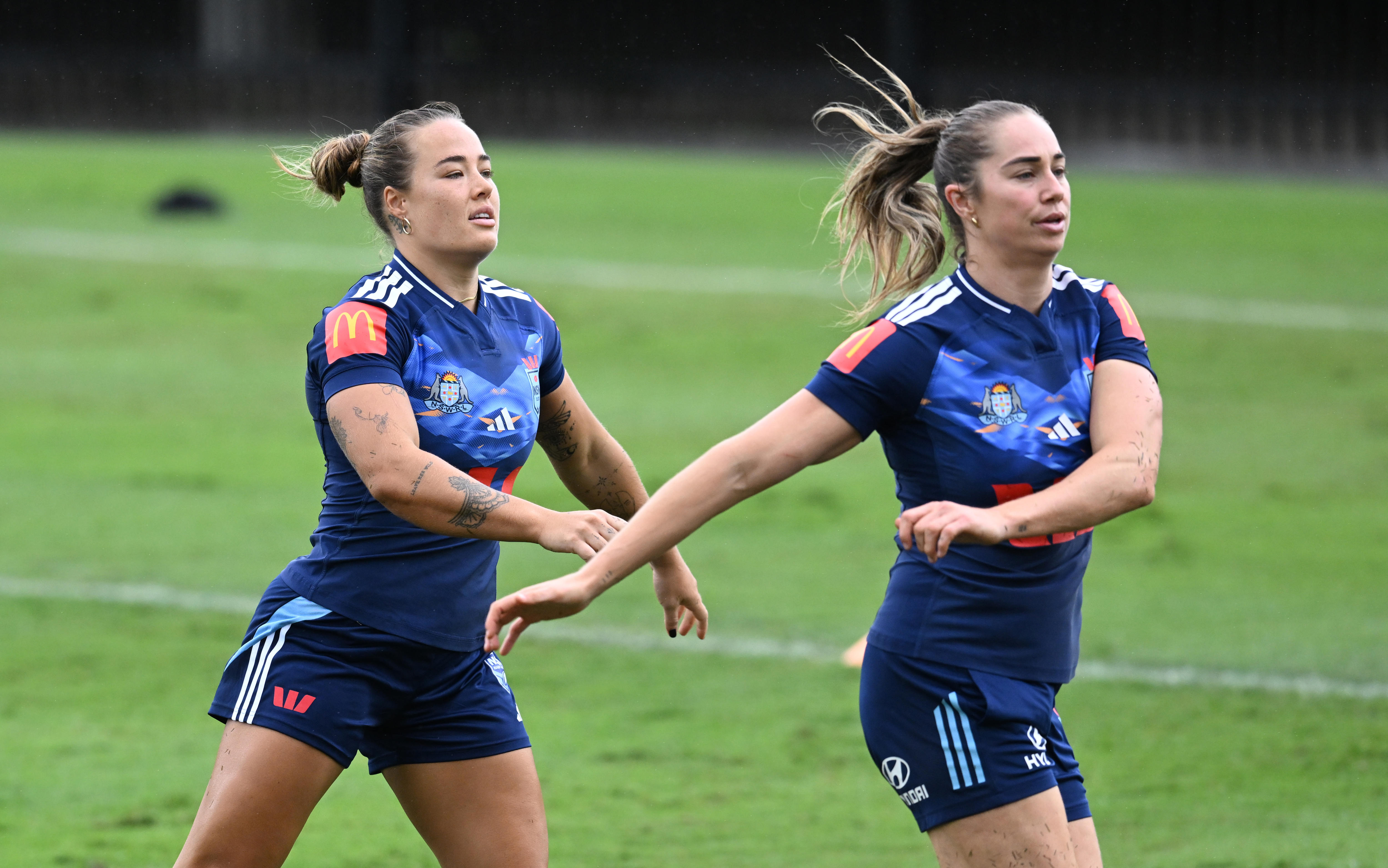 Duas mulheres se aquecem antes de uma sessão de treinamento da liga de rugby