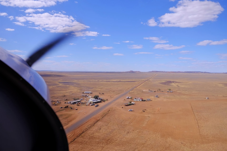 The view from a plane looking down over a handful of buildings among vast, flat plains.