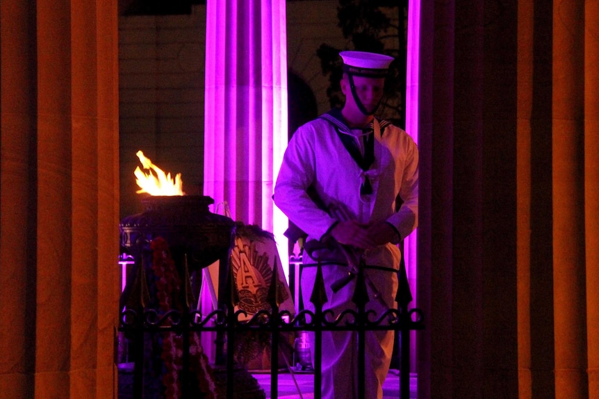 A member of the Catafalque Party, head bowed, stands next to the Eternal Flame in the Cenotaph.