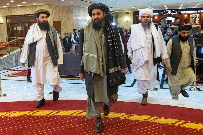 Men in traditional Afghan attire walk through a hotel lobby