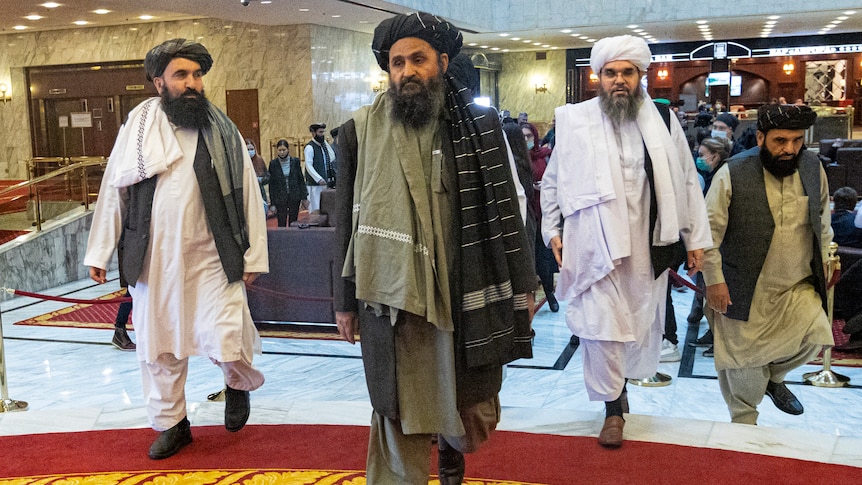Men in traditional Afghan attire walk through a hotel lobby