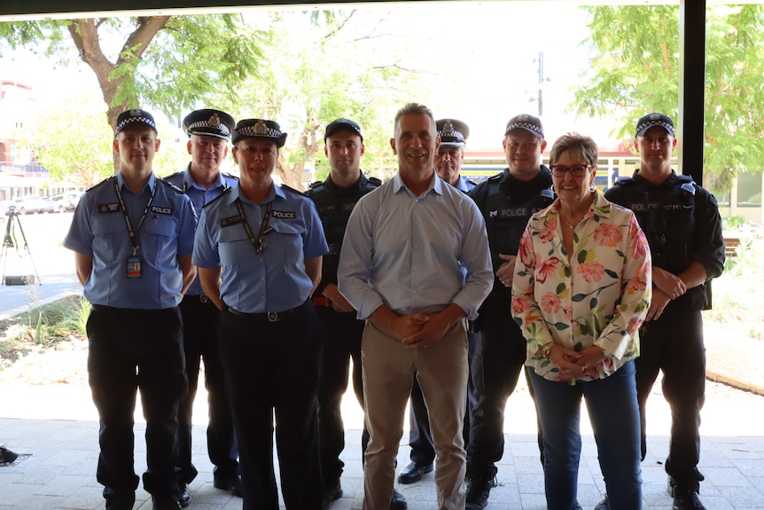 A man and woman stand with a group of police officers