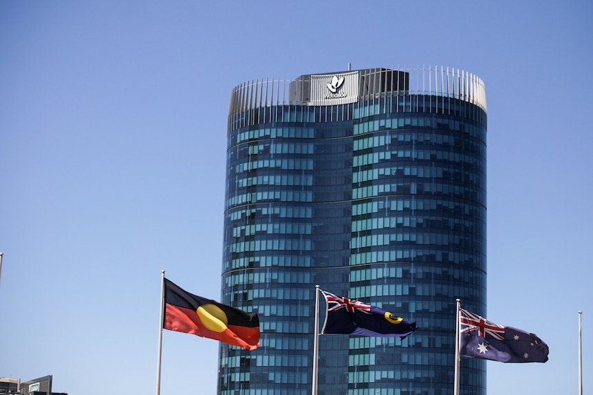 Woodside's tall building with an Aboriginal, WA and Australian flag in the foreground.